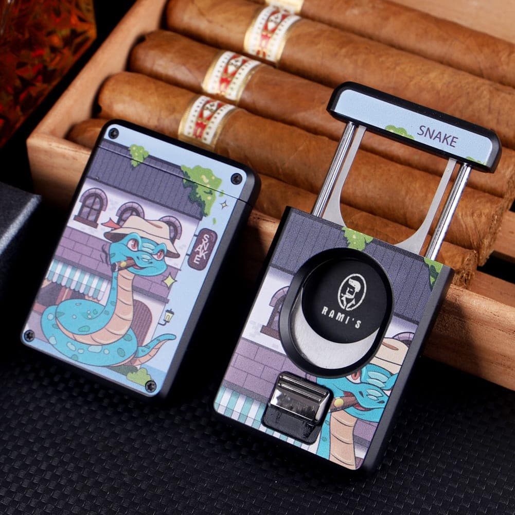 Front and back view of Rami’s Year of the Snake Cigar Cutter resting on an open wooden cigar box, showing stainless steel blades and zinc alloy body