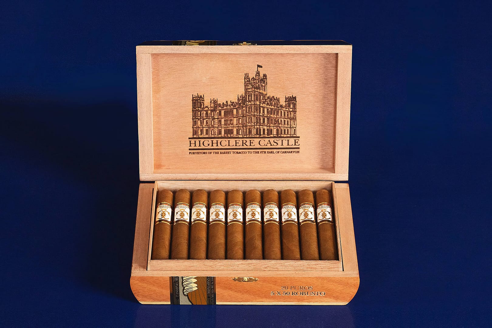 Open box of Highclere Castle cigars, featuring golden-brown wrappers neatly arranged inside an elegant, crest-embossed box