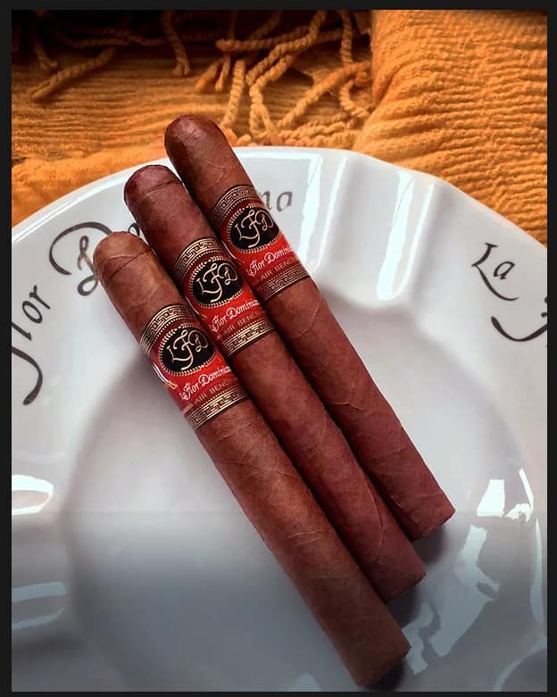 Three La Flor Dominicana Air Bender Double Press cigars resting elegantly on a ceramic dish, showcasing their box-pressed shape and rich brown wrappers.