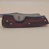 Rami's cigar knife with red wood handle and stainless steel blade displayed on a neutral background
