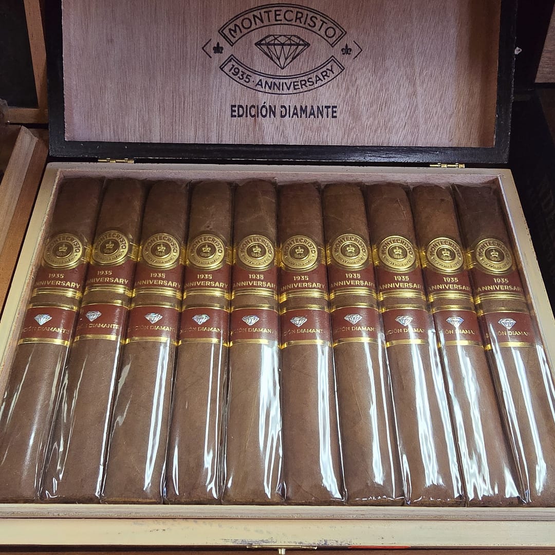 Open box of Montecristo 1935 Anniversary Edición Diamante Grande cigars with luxurious Nicaraguan wrappers and gold-accented presentation.