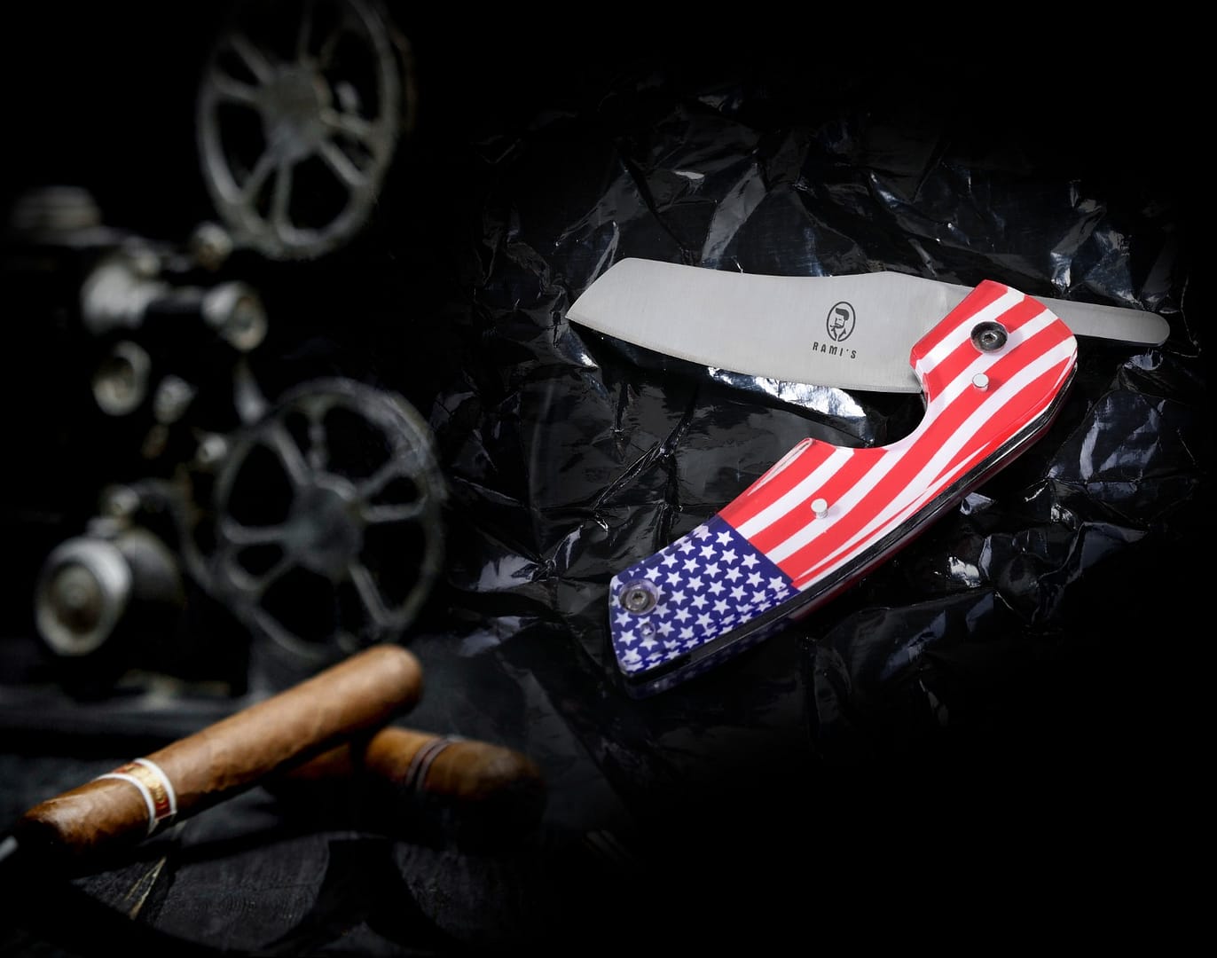 Rami’s Cigar Knives open, showing sharp blades and handles, placed next to a cigar to illustrate cutting purpose