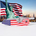 Rami’s American Flag Cigar Knife closed, placed in front of the Statue of Liberty and an American flag, highlighting the patriotic handle and sleek blade