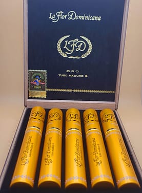 Open box of La Flor Dominicana Oro Tubo Maduro cigars, each housed in a sleek, shiny golden tube, arranged neatly inside a luxurious wooden box.