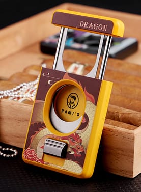 Rami’s Year of the Dragon Cigar Cutter in silver finish placed beside a wooden cigar box