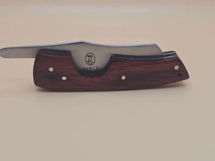 Rami's cigar knife with red wood handle and stainless steel blade displayed on a neutral background