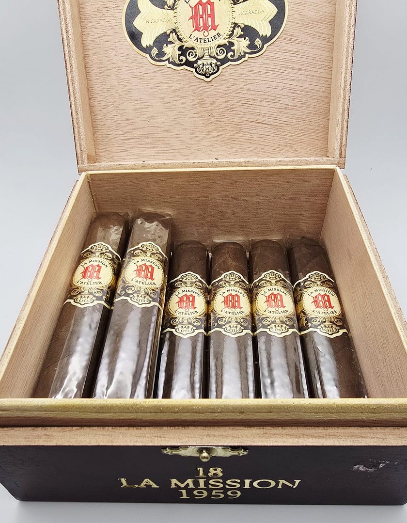 Open box of La Mission du L'Atelier 1959 cigars with dark San Andrés wrappers and elegant red-and-gold bands.