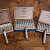 Open box of Aganorsa Leaf Anniversario cigars, featuring one of each wrapper type, showcasing their elegant construction and rich, varied wrappers.