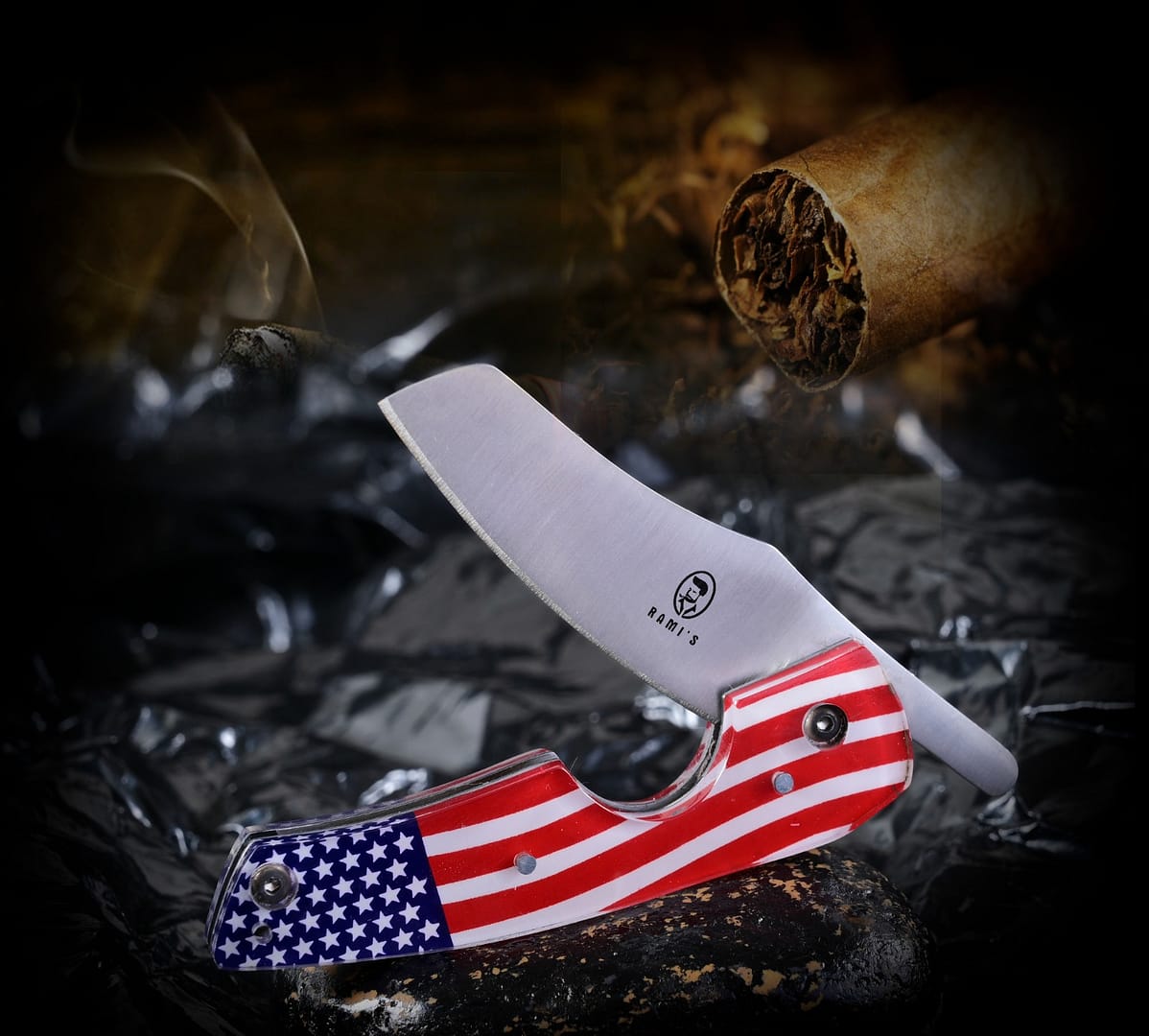 Rami’s American Flag Cigar Knife open, showing sharp blade and patriotic handle, with cigars arranged in the background