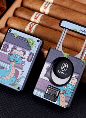 Front and back view of Rami’s Year of the Snake Cigar Cutter resting on an open wooden cigar box, showing stainless steel blades and zinc alloy body